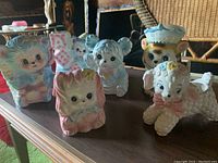 Six pastel-colored ceramic nursery planters in animal shapes arranged on a wooden surface.