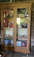 Front view of the oak wood display case showing glass doors with shelves holding various items (not included in sale).