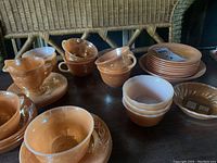 Overview of the Peach Lustre tea set with cups, saucers, and bowls arranged on a table under wicker chairs.