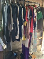 Photo of assorted vintage dresses, bathing suits, and tops on rack, various colors and fabrics visible