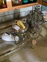 Overview of the vintage kettle, enamel chamber pot, metal candle holder, and iron boat on glass table