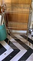 Full front view of the larger 3-tier vintage metal record rack showing vertical wire slots and curved handles.