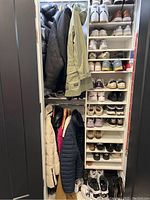 Full view of the closet shelving and hanging section filled with coats and shoes.