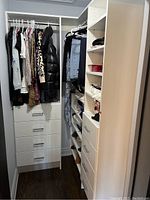Overall view of both closet organizer sections installed side by side, showing drawers, shelves, and hanging rods loaded with clothing.