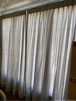 Curtain panels drawn closed letting filtered light through, showing pleated lined curtains with subtle pattern.