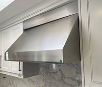 Front view of installed stainless steel range hood vent under cabinets