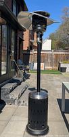 Full view of the propane patio heater showing standing height, cylindrical base, black pole, and bent stainless steel reflector hood.