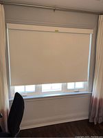 Front view of the roller blinds fully lowered, showing white opaque fabric and matching valance above.