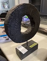 Front view of the circular wood and metal sculpture with visible texture and metal base