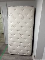 Front view of the taller twin mattress with white organic cotton fabric upholstery showing the tufted pattern and floral print.