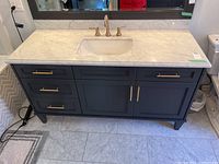 Front view of navy painted wood vanity showing marble top, sink, faucet, drawers, and cabinet doors