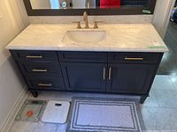 Front view of vanity showing marble countertop with under mount sink, brushed gold faucet, two drawers and double cabinet doors