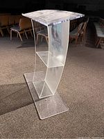 Front side view of clear acrylic podium with curved shape and etched design visible.
