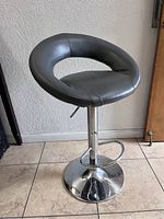 Grey padded swivel bar stool with chrome pedestal base, footrest, and adjustable height lever