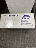 Boxed Sunset Master Builder 42-inch white hugger ceiling fan with 4 blades and 3-speed forward/reverse control, sealed in original packaging.