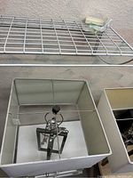 Close-up of one lamp inside white square shade showing silver inner frame and bulb holder on geometric metal base.