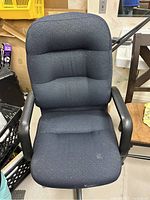 Front view of blue fabric office chair showing the padded seat and backrest with some stains visible