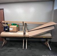 Photo showing stacked children's desks with flat wooden tops and painted legs; used condition with visible scratches and paint wear