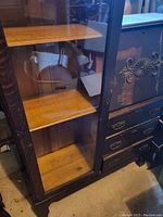 Front view of the glass-front wooden display cabinet section with shelves inside, showing antique wood grain.