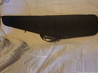 Full view of the black padded soft case lying flat showing its tapered shape and handle.