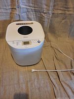 Top view photo of the Oster bread maker showing its overall design, power cord, and lid with round window.