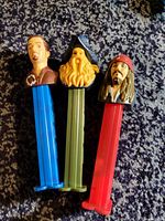Photo showing three Pirates of the Caribbean PEZ candy dispensers with character heads including Jack Sparrow, Davy Jones, and Will Turner on differently colored bases.