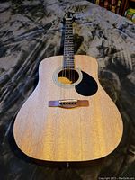Full body view of the mahogany finish acoustic guitar with black pickguard and rosewood bridge.