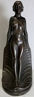 Front view of the cast metal nude woman figurine with Art Nouveau stylized shell backdrop.