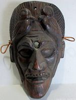 Front view of the hand carved wood mask showing facial features and birds on top sides.