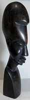 Side angle showing elongated head and carved facial details.