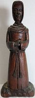 Full frontal view of the wooden monk statue showing standing pose and carved base.