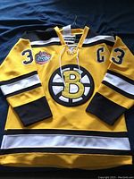 Full view of yellow Boston Bruins jersey with black and white accents, number 33 on sleeves and chest, 'C' captain letter on left chest.