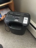 Full view of the Fellows black paper shredder with shredded paper visible in the bin and power cord on the side.