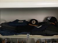 Wide view of folded jeans, sweaters, and baseball caps on a shelf
