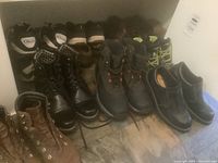 Photo showing multiple pairs of men's shoes including black leather boots, brown boots, black golf shoes, and casual shoes.