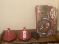 Photo of two red Moroccan-style tagine cookware pots and other kitchen items on a wooden surface.