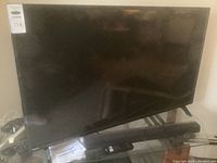 Front view of Philips 49" TV on stand with soundbar beneath and cables at base