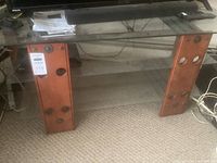 Full view of the three tier TV stand showing glass shelves, wood vertical supports with metal circular accents.