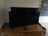 Front view of the Vizio 43-inch TV showing screen and remote on wooden surface.