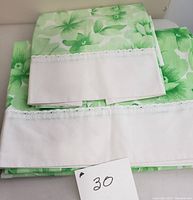 Folded vintage green floral Wabasso sheet showing white eyelet lace trim detail