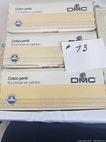 Boxes of vintage DMC Cotton Perle embroidery thread stacked, showing the DMC branding and packaging.