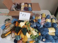 Photo of assorted skeins of wool tapestry yarn in various colors laid out with some in a box