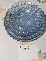 Three rimmed sapphire blue bowls with bubble glass texture all stacked in one image on floral cloth