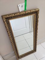 Full view of the rectangular framed mirror leaning against wall showing overall size and frame style