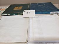 Two boxes of men's white handkerchiefs, one with six and one with four, showing unopened condition and box labels.