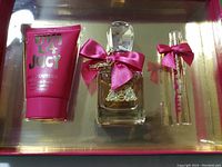 Photo of Viva La Juicy gift set contained in clear display box, showing body souffle tube, perfume bottle, and two smaller spray bottles all decorated with pink bows.