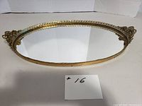 Front angle view of the oval mirrored vanity tray showing reflective surface and gold filigree handles