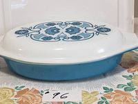 Side view of vintage Pyrex casserole with lid showing blue base and floral lid pattern