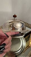 Side close-up of the muffin serving dome, showcasing the reflective surface and finial knob detail.