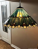 Side view of the blue slag glass shade fully illuminated, showing stained glass pattern and scalloped edge